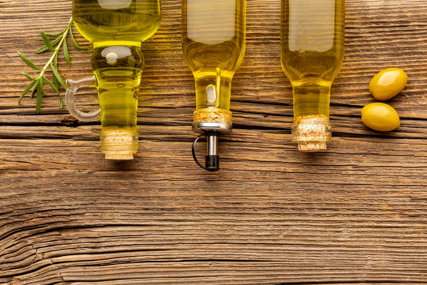 Tres botellas de aceite de oliva con tapón de corcho sobre una mesa de madera