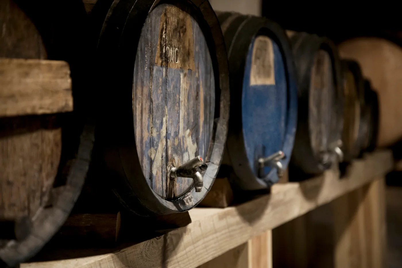 Botas de madera alineadas en la penumbra de una bodega de crianza