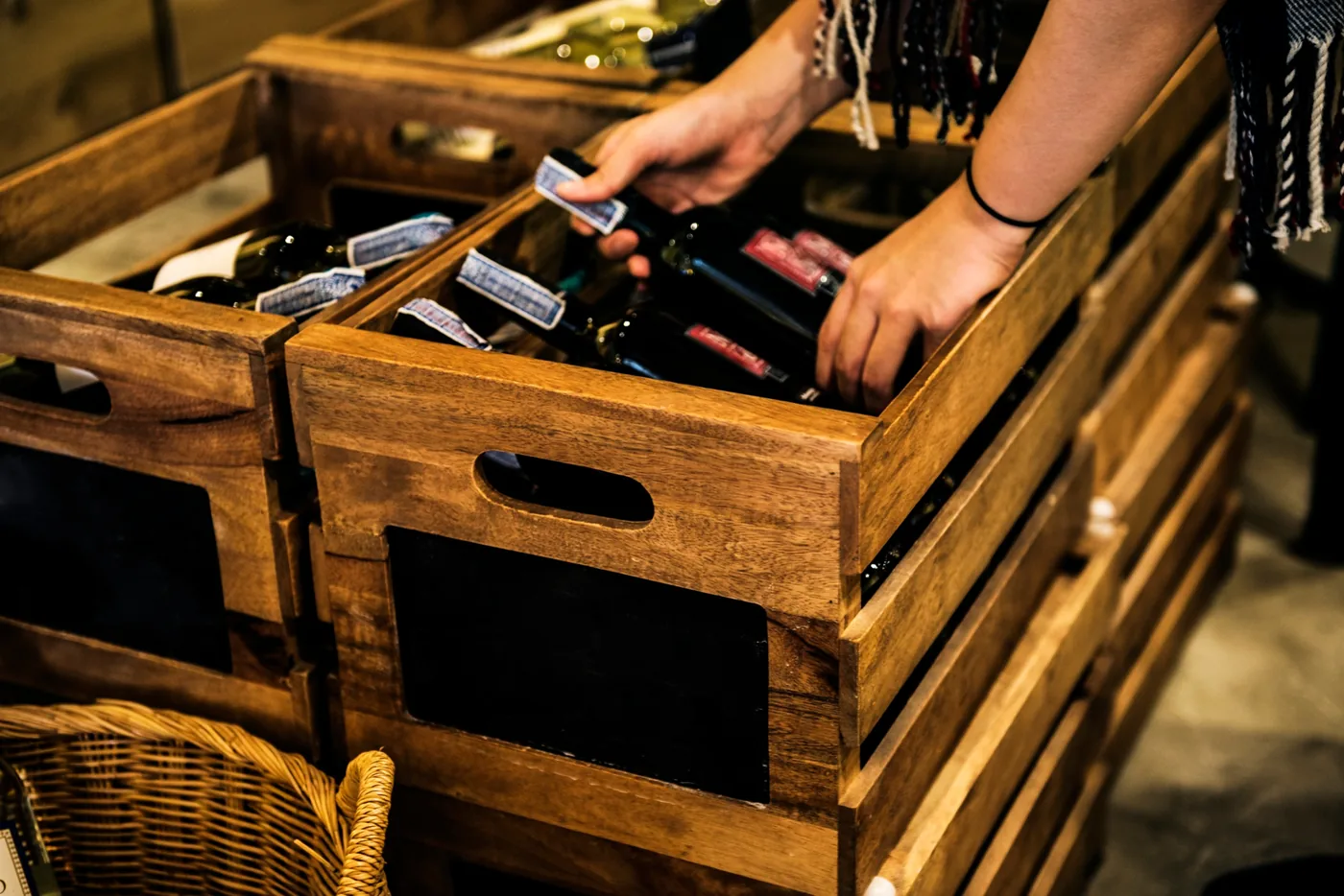 Manos colocando botellas de vino en cajas de madera